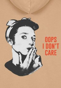 Felpa marrone con un grafiche in bianco e nero di una persona con un cerchietto, accompagnata dalla scritta "OOPS I DON'T CARE" in arancione.