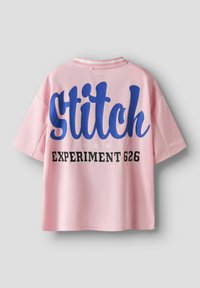 T-shirt rose à manches courtes avec un grand texte "Stitch" en bleu et "EXPERIMENT 626" en noir, avec un design de tissu texturé.