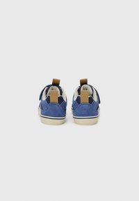 Baskets en suède bleu avec un intérieur crème, dotées d'une sangle Velcro et de deux languettes texturées sur le talon. Semelle en caoutchouc de couleur claire.