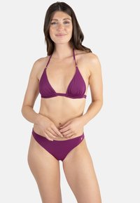 Ensemble bikini violet comprenant un haut triangulaire avec bretelles nouées au cou et détails froncés, accompagné d'un bas taille basse assorti.