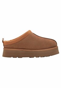 Brun slip-on sko med en blød ruskindsoverflade, der har en herringbone-mønstret krave og en tyk gummisål for ekstra støtte.