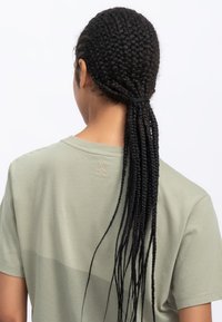 T-shirt verde chiaro con maniche corte, caratterizzato da un design minimalista e un piccolo logo ricamato sul retro. Tessuto liscio e vestibilità rilassata.