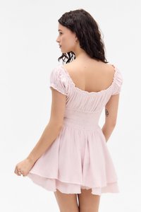 Vestido rosa claro con mangas abullonadas, cuerpo fruncido y falda acampanada. Fabricado con una tela suave de acabado texturizado.
