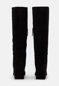 Bottes hautes jusqu'au genou en daim noir avec un talon carré, dotées de deux fermetures éclair latérales et d'une texture lisse.