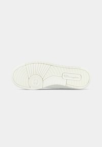 Λευκή σόλα αθλητικού παπουτσιού με υφή από καουτσούκ, με κυκλικό λογότυπο και οριζόντιες αυλακώσεις για καλύτερη πρόσφυση. Ομαλές άκρες και ελάχιστες λεπτομέρειες.