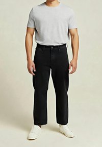 Černé džíny s vysokým pasem a volným střihem, doplněné světle šedým tričkem s krátkým rukávem a bílými slip-on botami.