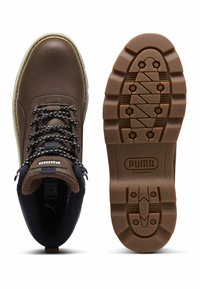 Botas de senderismo de cuero marrón con cordones negros y beige, cuello acolchado negro y suela de goma resistente con patrón de banda de rodadura PumaGrip.