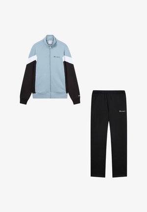 Chándal con chaqueta de cremallera azul claro que presenta paneles en negro y blanco, y pantalones negros a juego. Ambos artículos tienen acentos de logo.