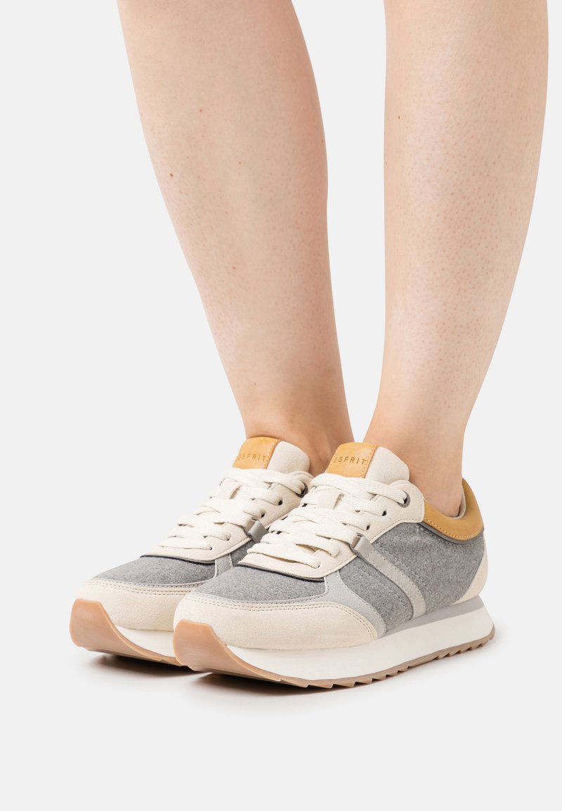 Gray and beige sneakers with a suede and felt texture, featuring a tan leather accent on the heel and cream-colored laces, retro design.