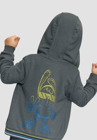 Dunkelgrauer Hoodie mit einer Kängurutasche und einem Grafikdruck eines Cartoon-Charakters in Gelb und Blau auf dem Rücken. Verfügt über eine Kapuze und gerippte Bündchen.