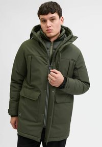 Groene gewatteerde parka-jack met een ritssluiting, meerdere voorzakken en een capuchon. Kenmerkt zich door een gewatteerde binnenvoering en ribgebreide manchetten.