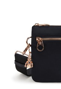 Borsa nera in nylon, con zip dorata, dettaglio con charm e tracolla intrecciata. Design rettangolare compatto con texture liscia.