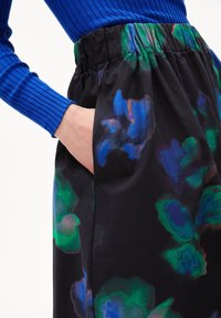 Jupe midi florale en tissu noir avec des motifs abstraits bleus et verts. Dotée d'une ceinture élastique et de poches latérales.