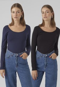 Langärmlige Tops aus navyblauem und schwarzem Baumwollstoff mit Rundhals-Ausschnitten, kombiniert mit hellblauen, hochgeschnittenen Jeans.
