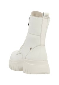 White ankle boot made from smooth leather, featuring a thick sole, textured accents, and a decorative zipper on the side for closure.