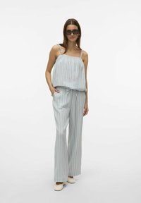 Ljusblå randig jumpsuit med tunna axelremmar, flödande topp, elastisk midja och vida ben. Texturerad tyg med avslappnad passform.
