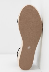 Black espadrille sandal sole, featuring a textured, light brown rubber bottom and a jute-covered midsole, size marked 37.