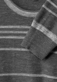 Grårandig tröja i mjukt tyg. Har en rund halsringning och kontrasterande ljusgrå horisontella ränder på en mörkare bakgrund.