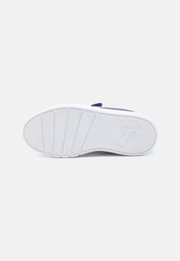Semelle de chaussure de sport blanche avec un motif de traction en zigzag, présentant une texture lisse et un petit logo en relief dans la zone du talon.
