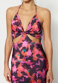 Flerfärgad halterneck-klänning med knyt-fram design och utskärningar, tillverkad av ett smidigt, glänsande tyg med abstrakta mönster.