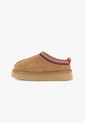Ruskohattu tummanruskea slippari beige-pohjalla, punavalkoisen kuviollisen reunuksen ja punaisen vetolenkin kanssa kantaosassa.