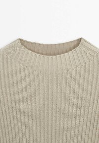 Beżowy sweter z dzianiny o prążkowanej fakturze i okrągłym dekolcie. Posiada subtelne ozdobne akcenty w okolicy ramion.