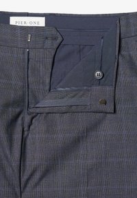 Pantaloni a quadri blu navy con texture liscia, multiple tasche, chiusura a bottone e un'etichetta che legge "PIER ONE."