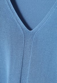 Hellblaues V-Ausschnitt-Strickoberteil mit glatter Textur, subtilen Rippen entlang des Halsausschnitts und nahtlosem Design.