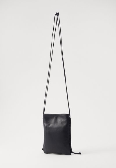 Borsa a tracolla in pelle nera con lunghe cinghie regolabili a cordoncino. Texture liscia, forma rettangolare e design minimalista.