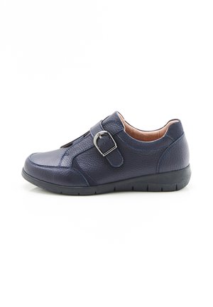 Zapato de cuero azul marino con un acabado texturizado, que presenta una correa lateral con una hebilla plateada y una suela flexible de goma negra.