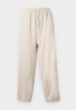 Pantaloni della tuta beige con vita elastica e coulisse. Presentano tasche laterali e polsini elastici alle caviglie. Tessuto morbido e liscio.