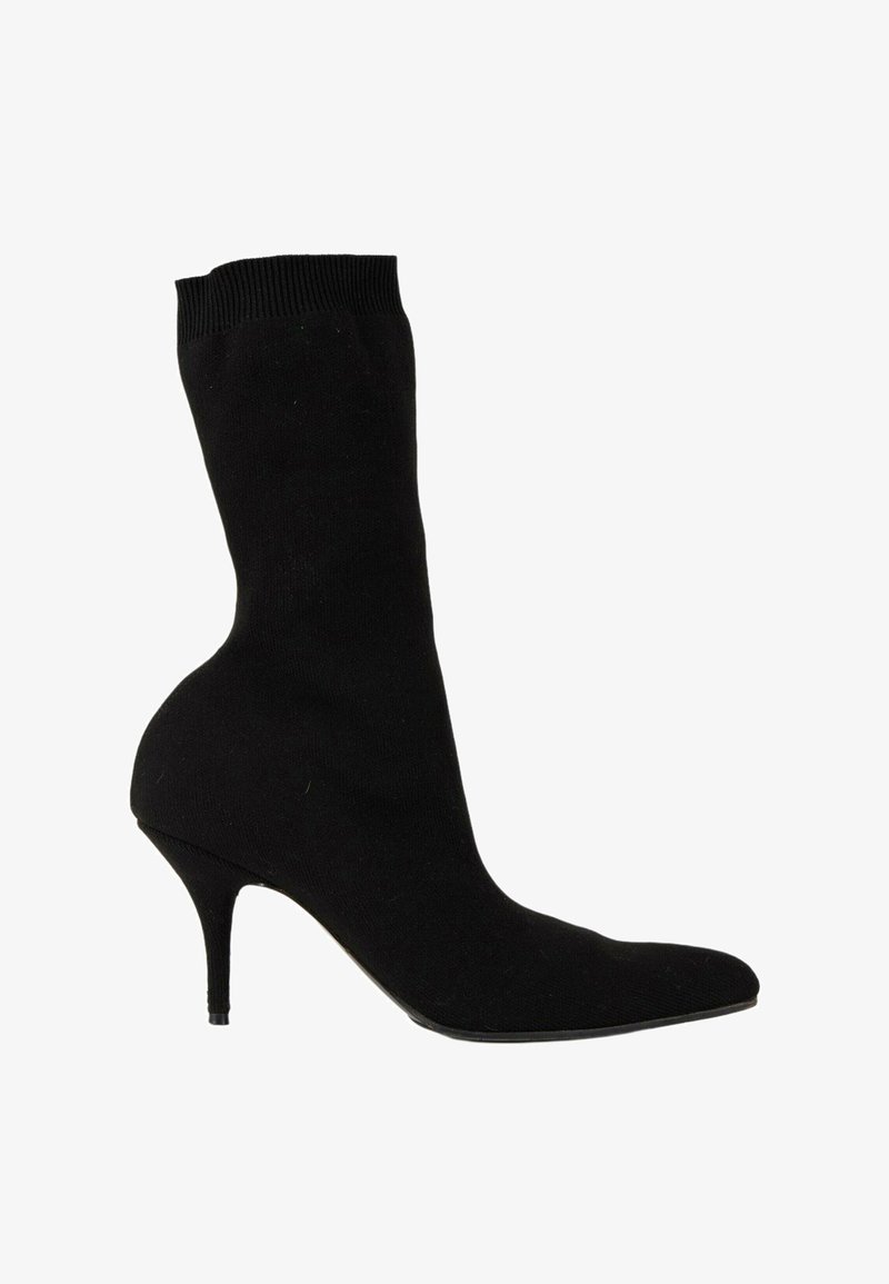 Bottine noire mi-mollet avec bout pointu et talon haut fin, en tissu stretch.