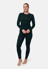Haut à manches longues thermal vert foncé et leggings assortis, fabriqués en tissu doux et extensible avec un design ajusté et de délicates finitions de couture.