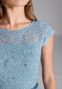 Himmelblaues Spitzendress mit floralen Mustern, Pailletten und einem gewellten Cap-Ärmel-Design, aus glattem Stoff.
