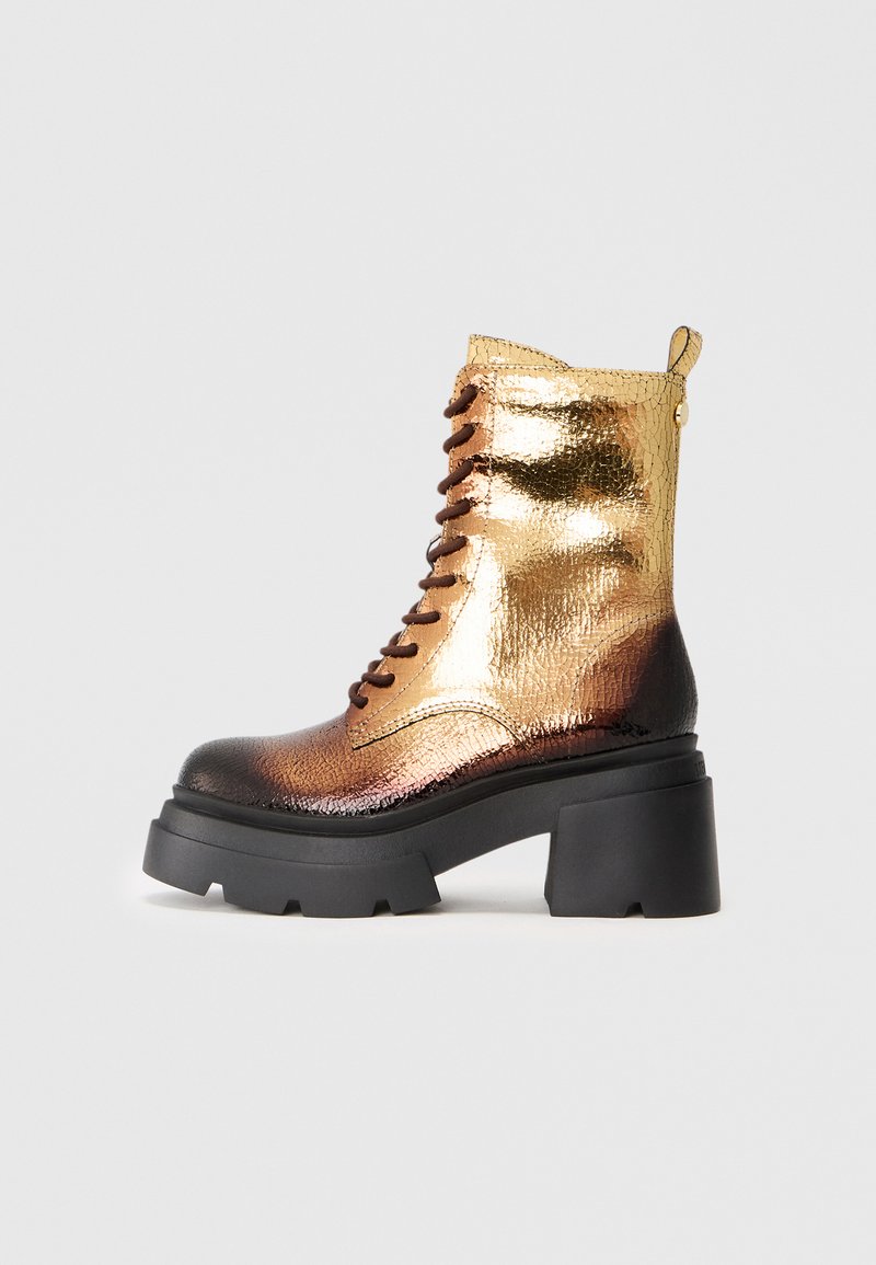 Botte de combat à lacets avec finition en or métallique et marron, surface texturée, talon noir épais et tirette.