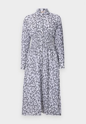 Svart og hvit blomstermønstret kjole med krage, lange ermer, smocket liv og flytende skjørt. Laget av lett stoff.