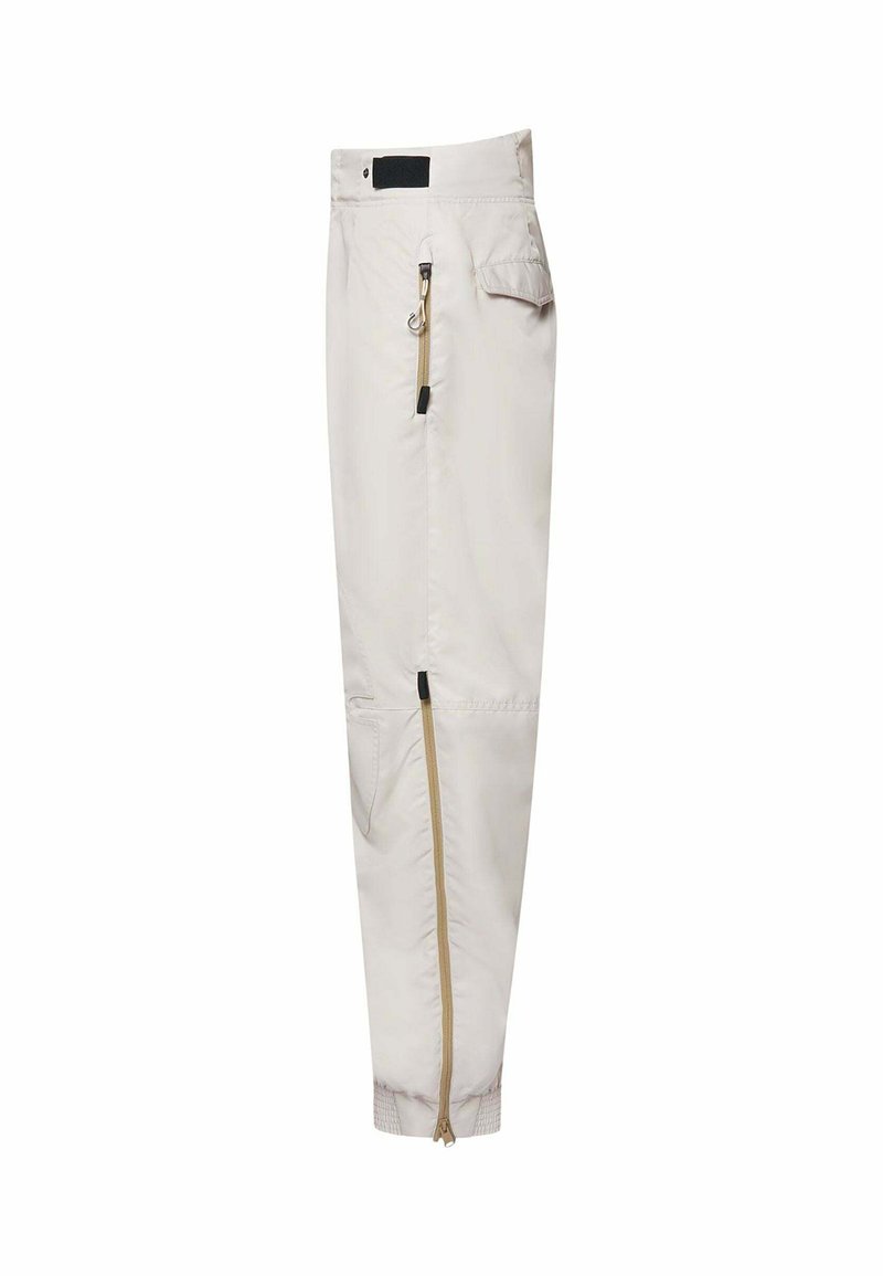 Helle beigen Hose mit lockerer Passform, ausgestattet mit einem seitlichen Reißverschluss, elastischen Bündchen und einer Gesäßtasche, aus einem leichten, glatten Stoff gefertigt.