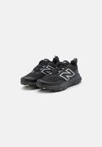 Black athletic shoes with a textured upper, reflective accents, and a speckled sole design. Features laces and a pull tab on the heel.