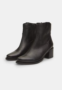 Botas de tobillo de cuero negro con un acabado texturizado, punta afilada, cremallera lateral y un tacón grueso. Presentan costuras decorativas.