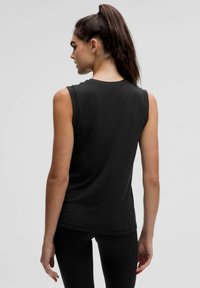 Czarny bezrękawnik wykonany z miękkiego materiału, z okrągłym dekoltem, dopasowanym krojem i gładką fakturą. Widok z tyłu ukazujący ramię i plecy.