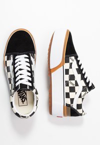 Zapatillas de lona a cuadros en blanco y negro con acentos de ante, cordones blancos y una suela gruesa de goma blanca y color caramelo.