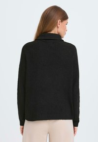 Pulover negru cu model răsucit, cu guler �înalt, mâneci lungi și o croială lejeră. Textura pare moale, cu un model de tricotare subtil și detalii la tiv.