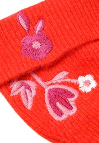 Piros kötött textil, bonyolult rózsaszín és fehér virágmintával hímzett, virág- és levélmintával. Puha tapintású, bordázott szerkezet.