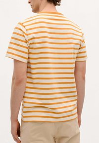 Camiseta de manga corta en suave algodón con rayas horizontales alternadas amarillas y blancas, que presenta un cuello redondo y un corte relajado.