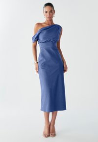 Vienos peties mėlyna suknelė su aptemptu liemeniu, lengvai krentančia medžiaga ir maksi ilgiu. Lygi tekstūra ir minimalistinis dizainas.
