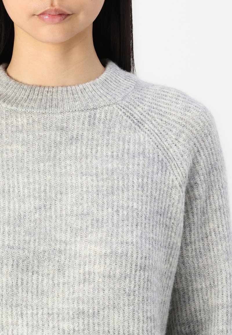 Grau gestrickter Pullover mit einem gerippten Muster und einem runden Ausschnitt. Verfügt über ein dezentes Muster und leicht herunterhängende Schulternähte.