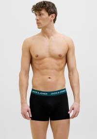 Schwarze Baumwollboxershorts mit grünem Bund, auf dem der Text "JACK & JONES" steht. Figurbetontes Design, glatte Textur und Oberschenkel-lange.