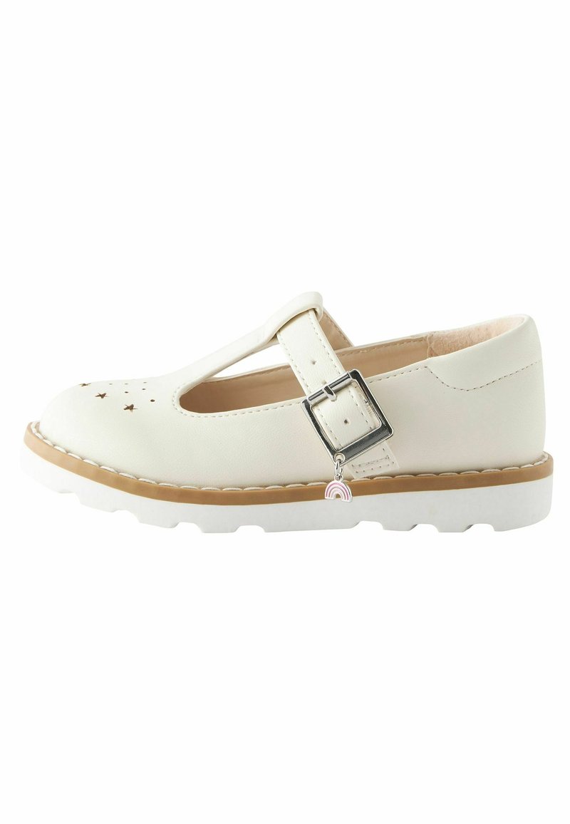 Chaussure Mary Jane couleur crème avec découpes en forme d'étoile sur l'avant, bride à boucle argentée, breloque arc-en-ciel, et semelle épaisse blanche avec bordure marron clair.