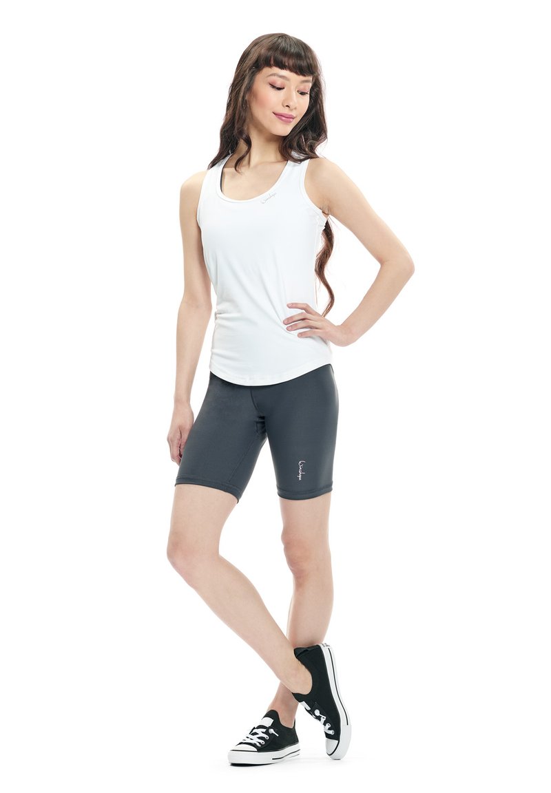 White sleeveless tank top paired with dark grey shorts. The outfit features a fitted design and soft fabric, complemented by black sneakers.