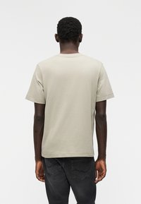 Ανοιχτό γκρι βαμβακερό t-shirt με κοντά μανίκια, κανονική εφαρμογή και στρογγυλή λαιμόκοψη. Διαθέτει ομαλή υφή χωρίς ορατά μοτίβα ή διακοσμητικά στοιχεία.